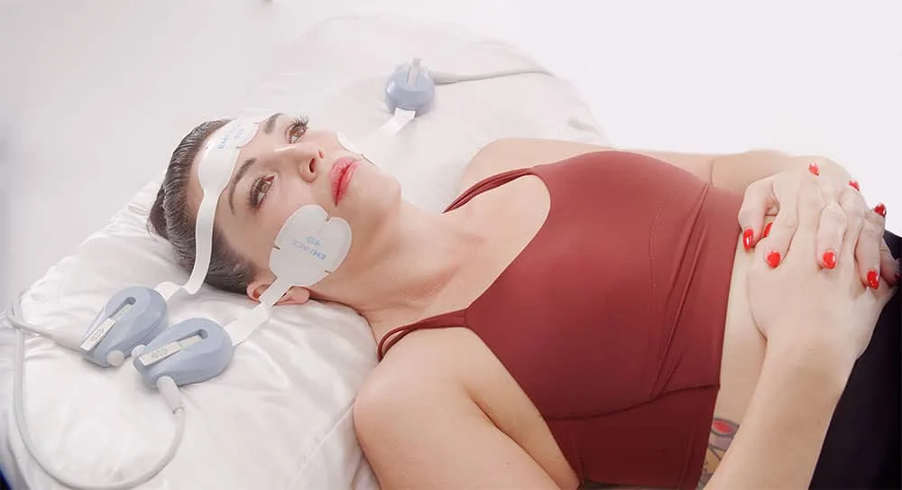 Woman lying down with facial applicators in place at our Korte van Eeghenstraat clinic, EMface facial toning Amsterdam